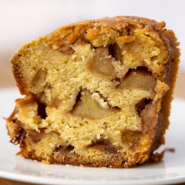 Close-up of a slice of Moish and Itzy's apple cake, revealing chunks of fruit within the golden crumb.