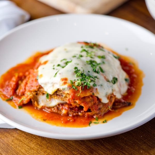 Moish and Itzy's lasagna, topped with melted cheese, tomato sauce, and fresh parsley.