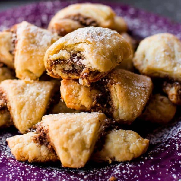 A close-up of Moish and Itzy's rugelach, dusted with powdered sugar, on a purple plate.