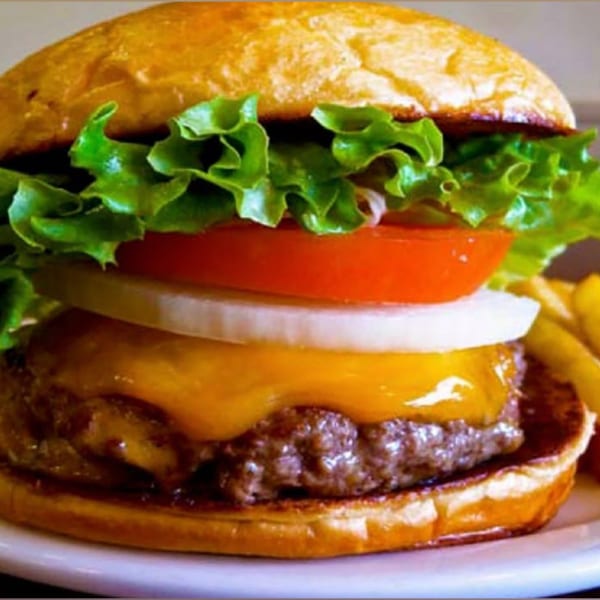A Moish and Itzy's cheeseburger with lettuce, tomato, onion, and melted cheese on a bun.