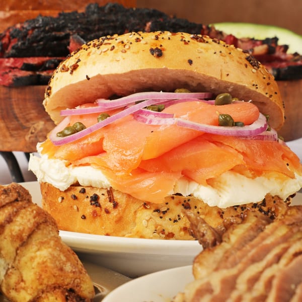 Close-up of a Moish and Itzy's everything bagel with lox, cream cheese, red onion, and capers.